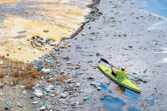 Ein Kayakfahrer fährt an einer vermüllten Küste