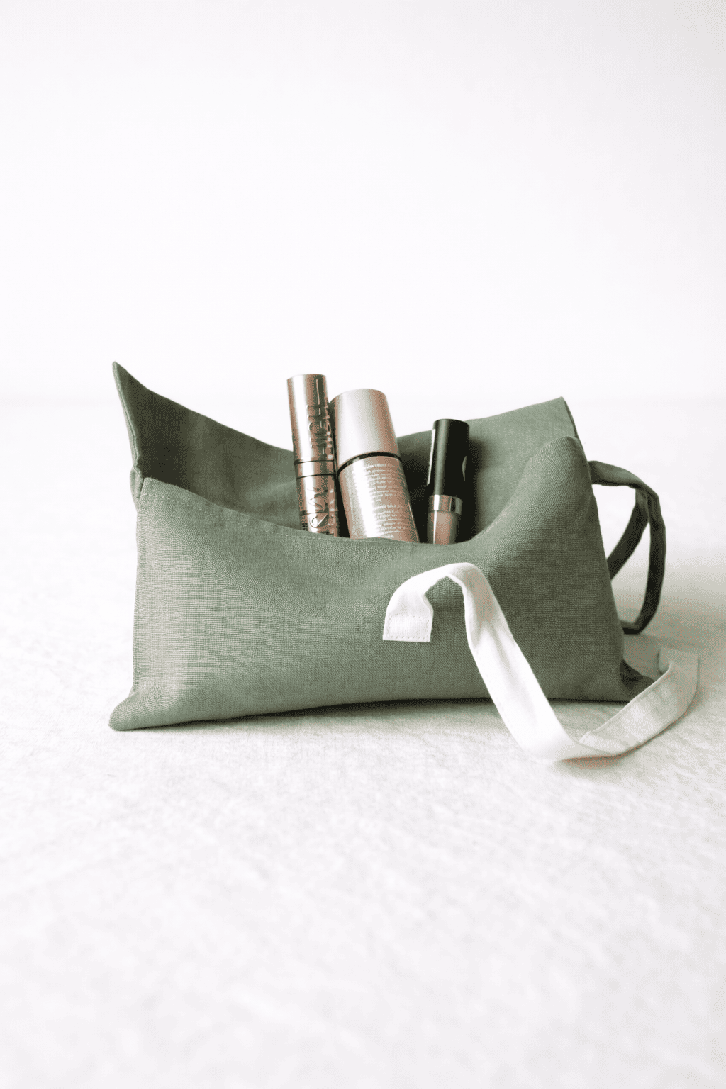 Geöffnete Grüne Kosmetiktasche aus Bio-Leinen mit weißen Schleifen