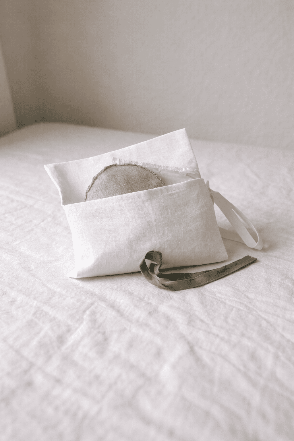 Geöffnete weiße Schminktasche aus Bio-Leinen mit grünen Schleifen