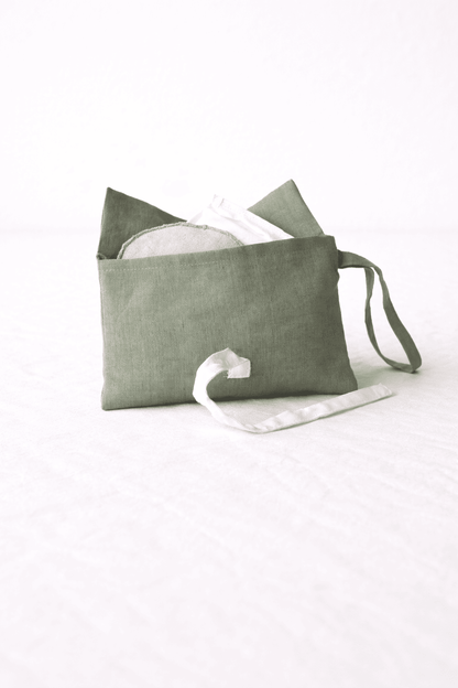 Geöffnete grüne Schminktasche aus Bio-Leinen mit weißen Schleifen